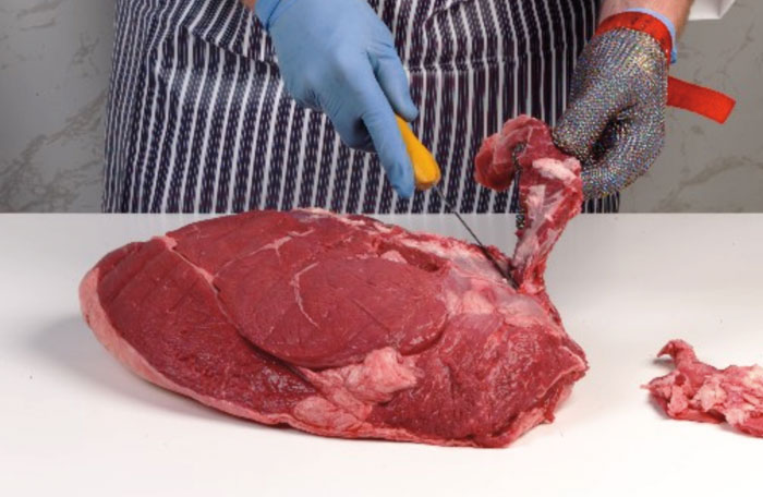 a person cutting meat on a cutting board